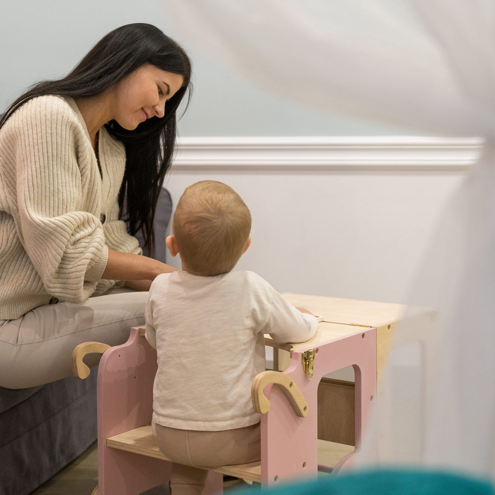 Kind sitzt auf 2in1 Lernturm umbaubar als Sitzmöbel für Kinder im gelben Kinderzimmer mit Montessori und Pikler Spielmöbel Design
