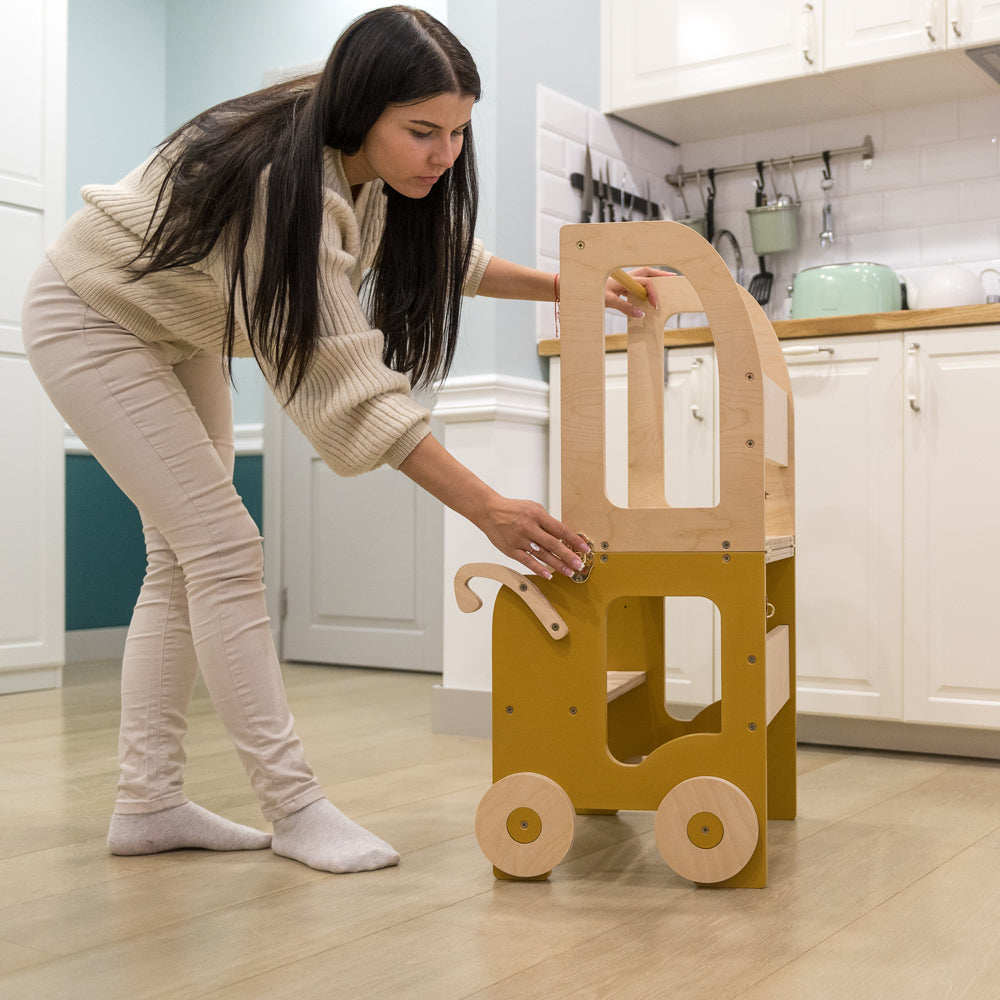 Frau baut 2in1 Lernturm um in gelbem Auto-Look, Teil der Spielmöbel und Sitzmöbel für Kinder im Montessori-Stil.