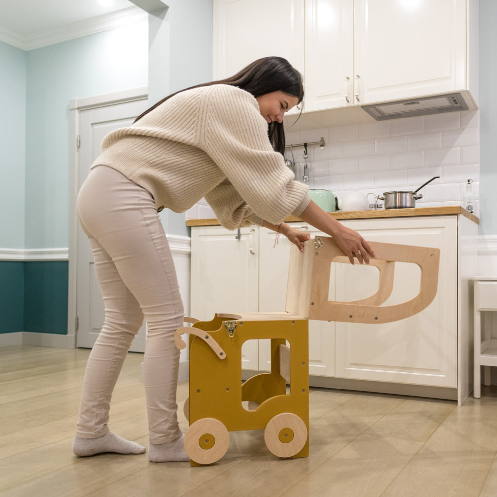 Frau baut 2in1 Lernturm in Auto-Optik um, vielseitiges Sitzmöbel für Kinder aus Spielmöbel und Montessori Kollektion in gelbem Kinderzimmer.