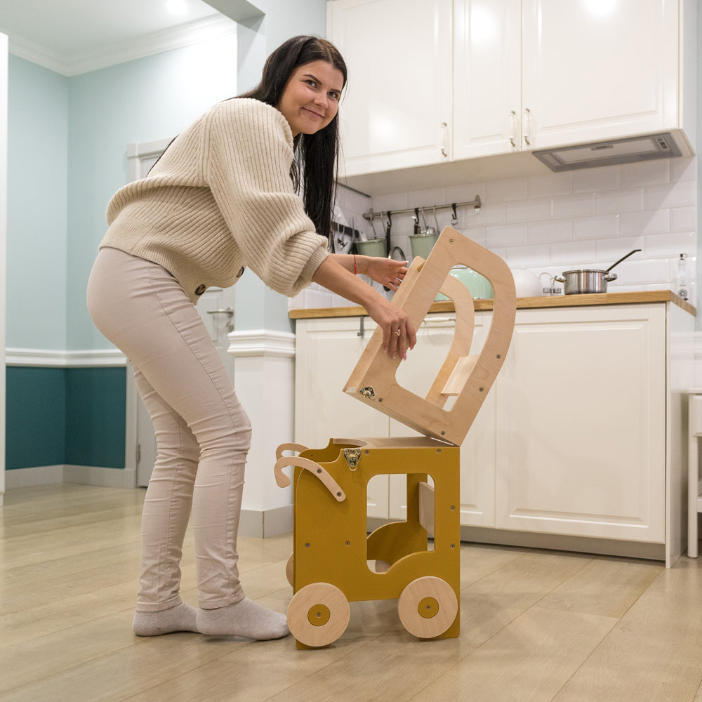 Frau stellt 2in1 Lernturm umbaubar als Küchenhelfer und Sitz-Tischset im Gelben Kinderzimmer mit Spielmöbeln und Montessori-Stil auf