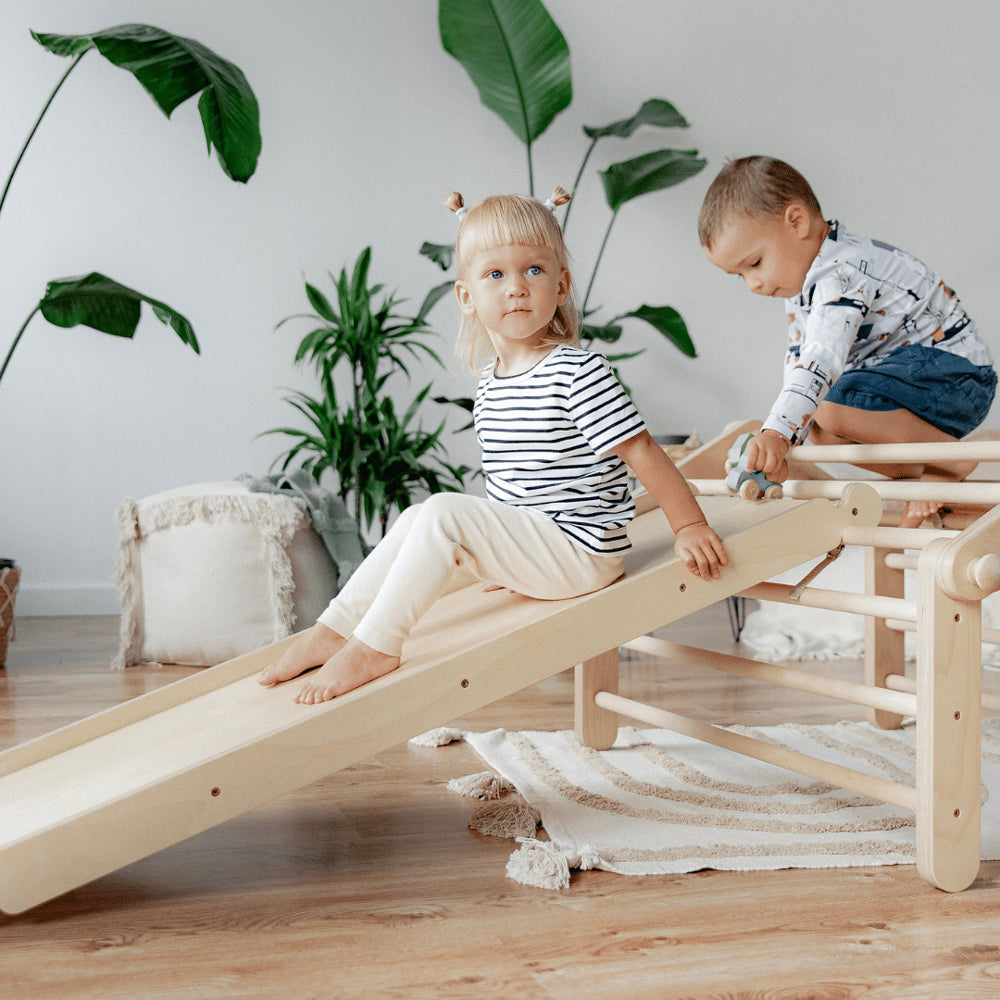 Kinder spielen auf natürlichem Holz-Pikler Kletterdreieck mit Rampe im Kinderzimmer, fördert Bewegung und motorische Entwicklung spielerisch.