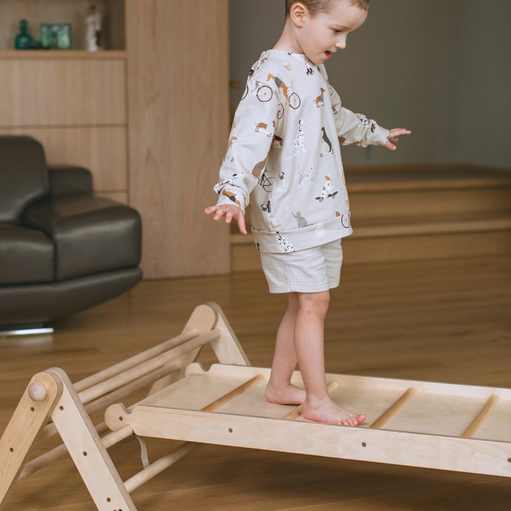 Kind balanciert auf dem natürlichen Pikler Kletterdreieck mit Rampe aus Holz, fördert Spiel & Bewegung Kinder in Spielmöbel Kollektion.