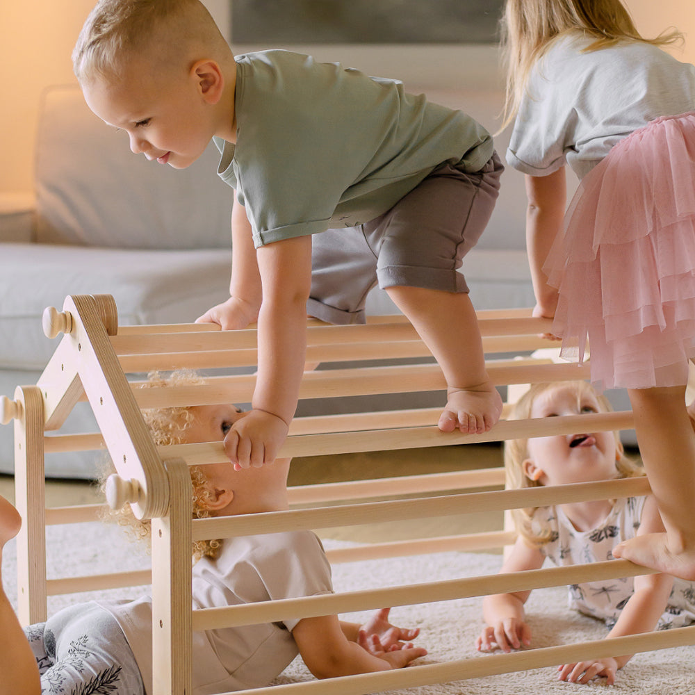 Kinder spielen gemeinsam an einem natürlichen Pikler Kletterdreieck mit Rampe aus Holz, ideal für Spiel & Bewegung Kinder und Montessori Lernen.