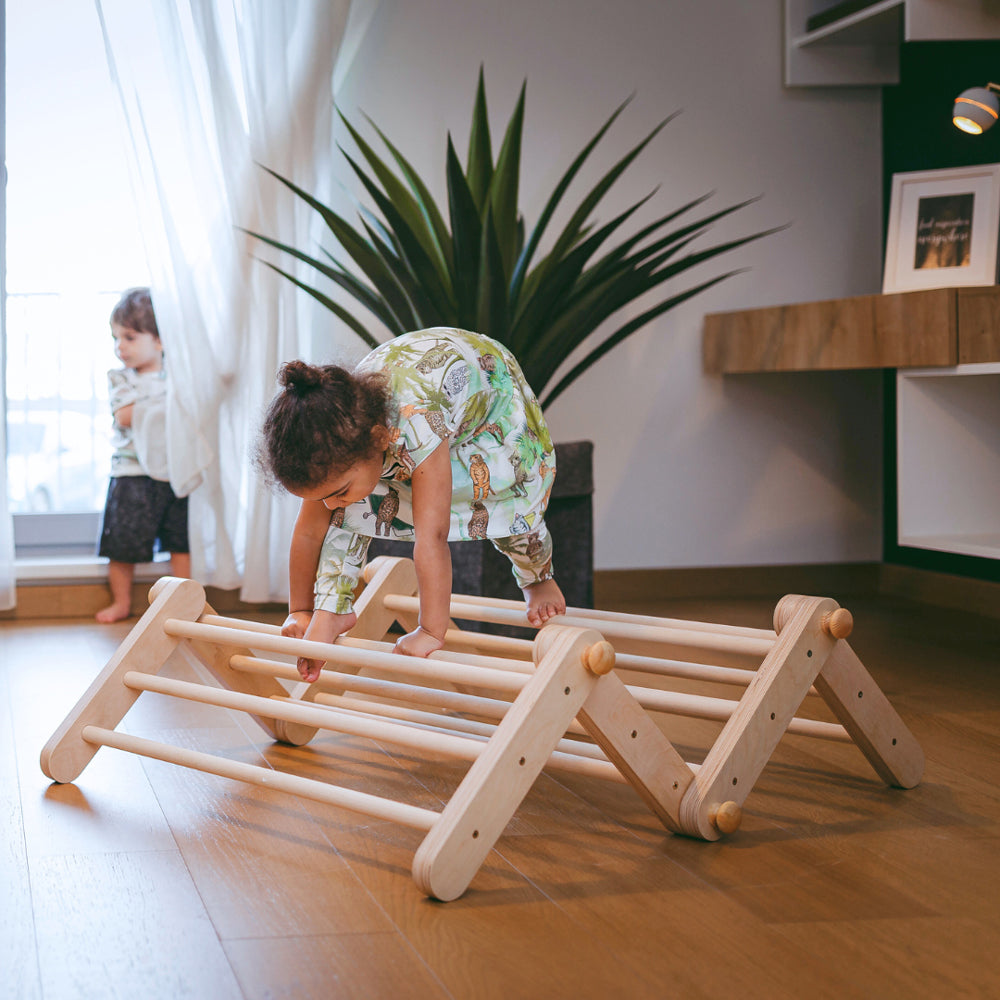 Kind spielt aktiv auf natürlichem Holz-Pikler Kletterdreieck aus Spielmöbel-Kollektion für Bewegung und Montessori Lernen