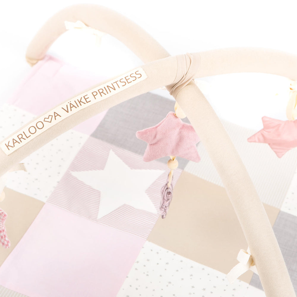 Activity Spieldecke mit Spielbogen in sanften Rosa- und Beigetönen, mit weichen Baumwollstoffen und rasselnden Sternen zur Förderung der Babyentwicklung.