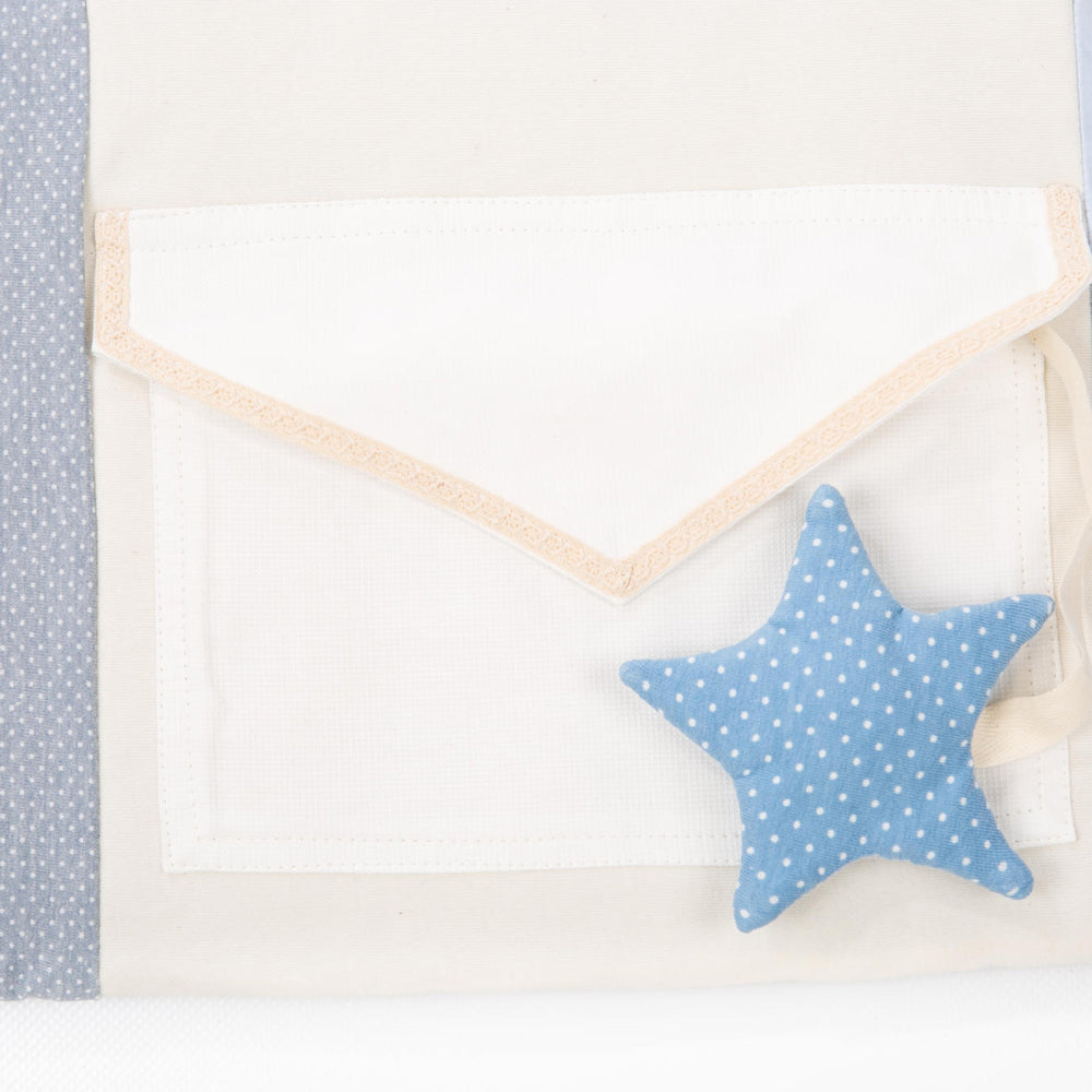 Blau gepunkteter Stoffstern neben weißer Stofftasche auf Bio-Baumwollspieldecke, sanfte Farben und weiche Materialien für Babys erstes Spielvergnügen.