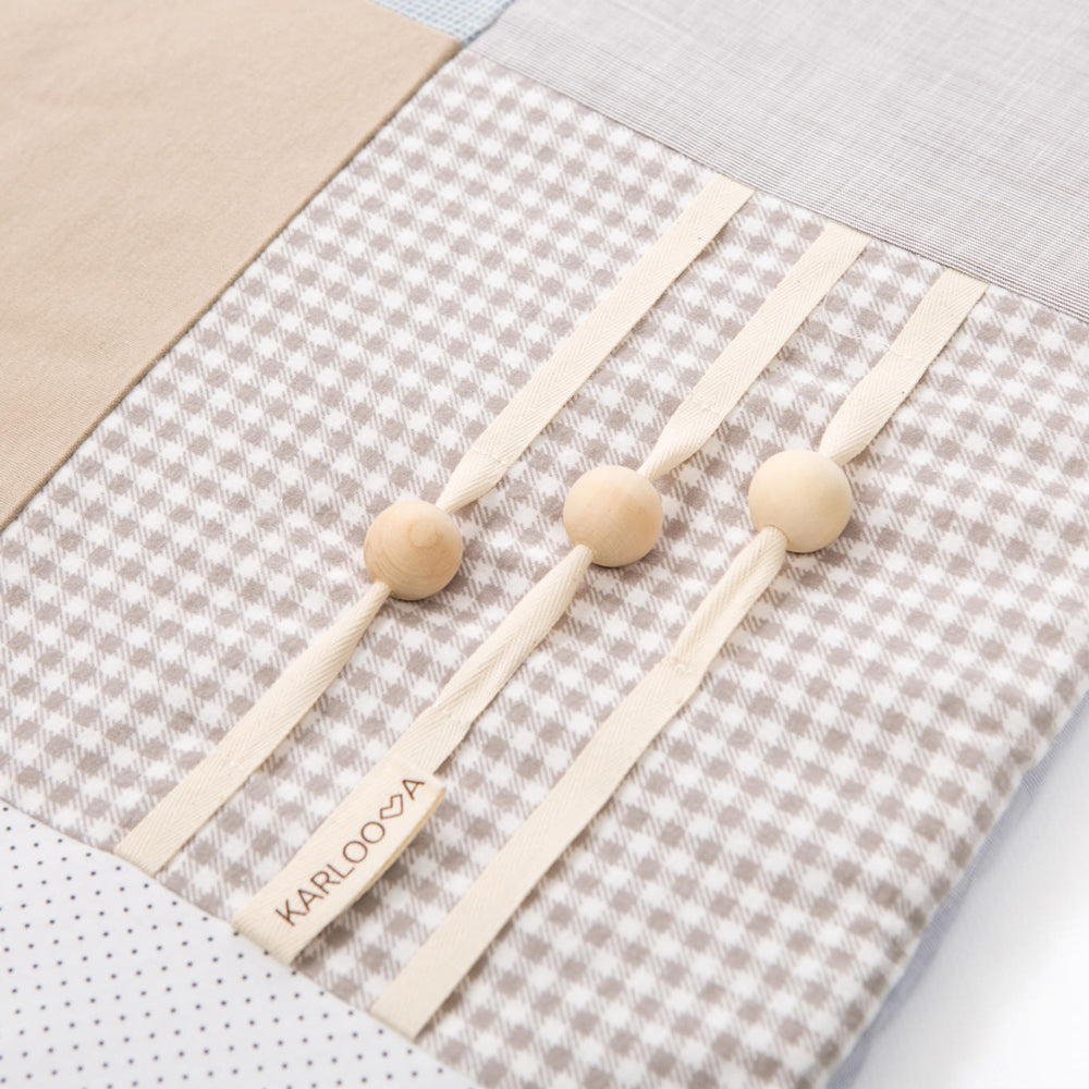 Weiche Bio Baumwoll-Krabbeldecke mit beige-blauem Patchworkmuster und Holzperlen zur Förderung motorischer Fähigkeiten.