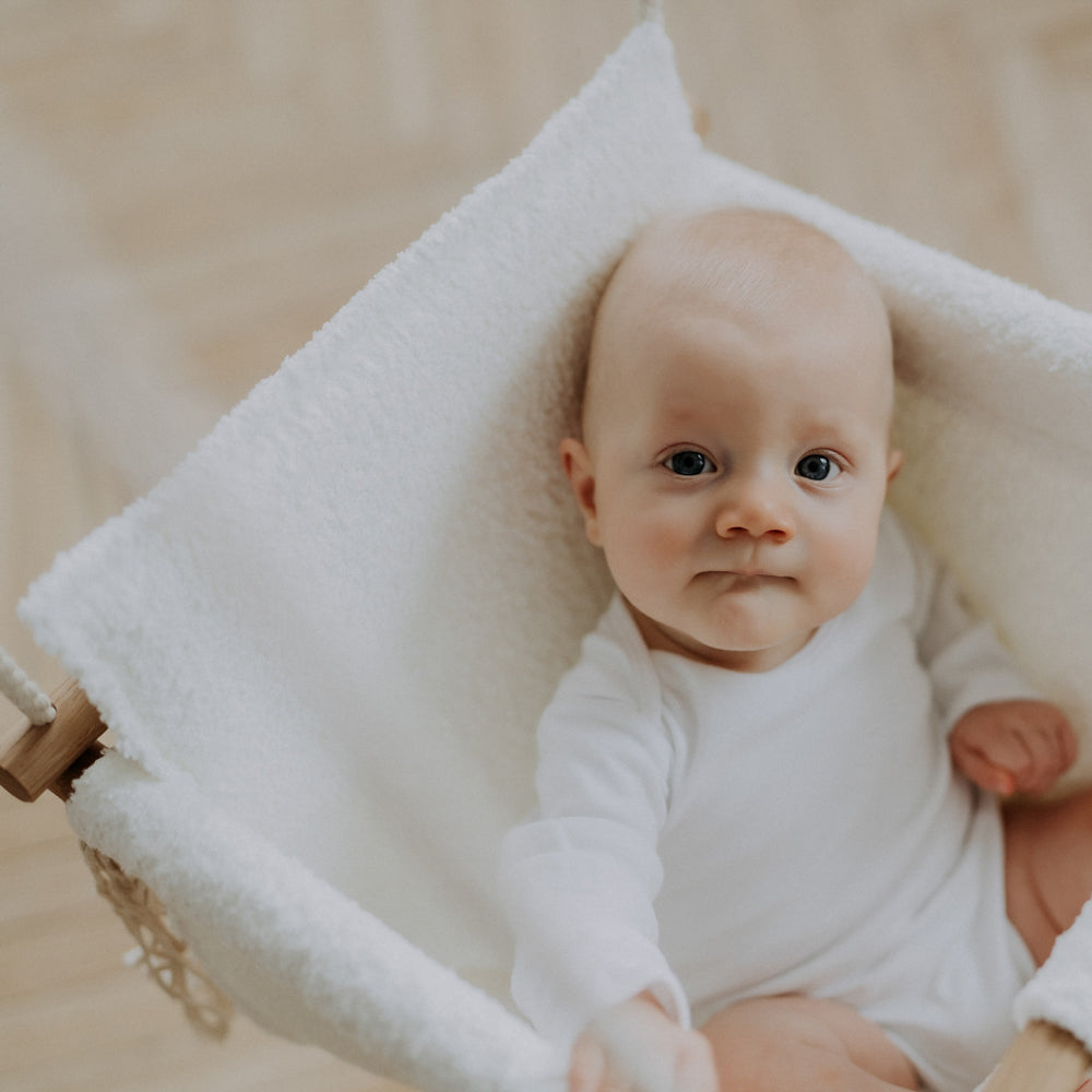 Baby in weißer Babyschaukel Swing Boucle für Innenbereiche aus der Kollektion Spielzeug & Spiele, Wipp- & Schaukelspielzeug, neu und sicher.