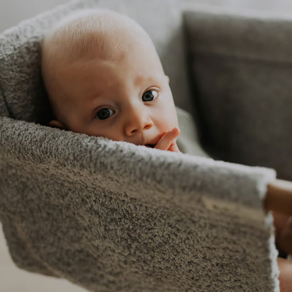 Kleines Baby entspannt in grauer Babyschaukel Swing Boucle für Innenbereiche aus der Kollektion Spiel & Bewegung Kinder Neu Spielmöbel