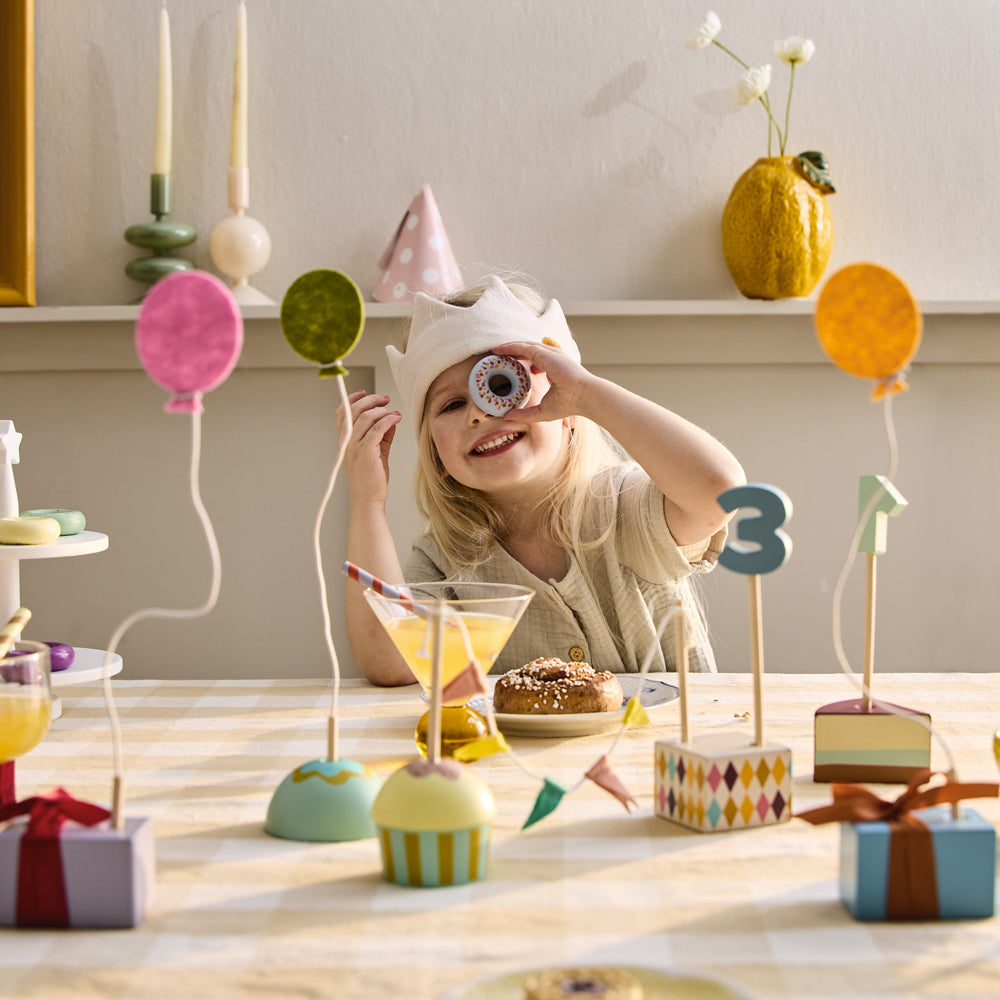 Kind feiert Geburtstag mit Geburtstagsdekoration-Set aus Holz, bunte Deko im gelben Kinderzimmer mit Spielzeug & Geschenke-Atmosphäre