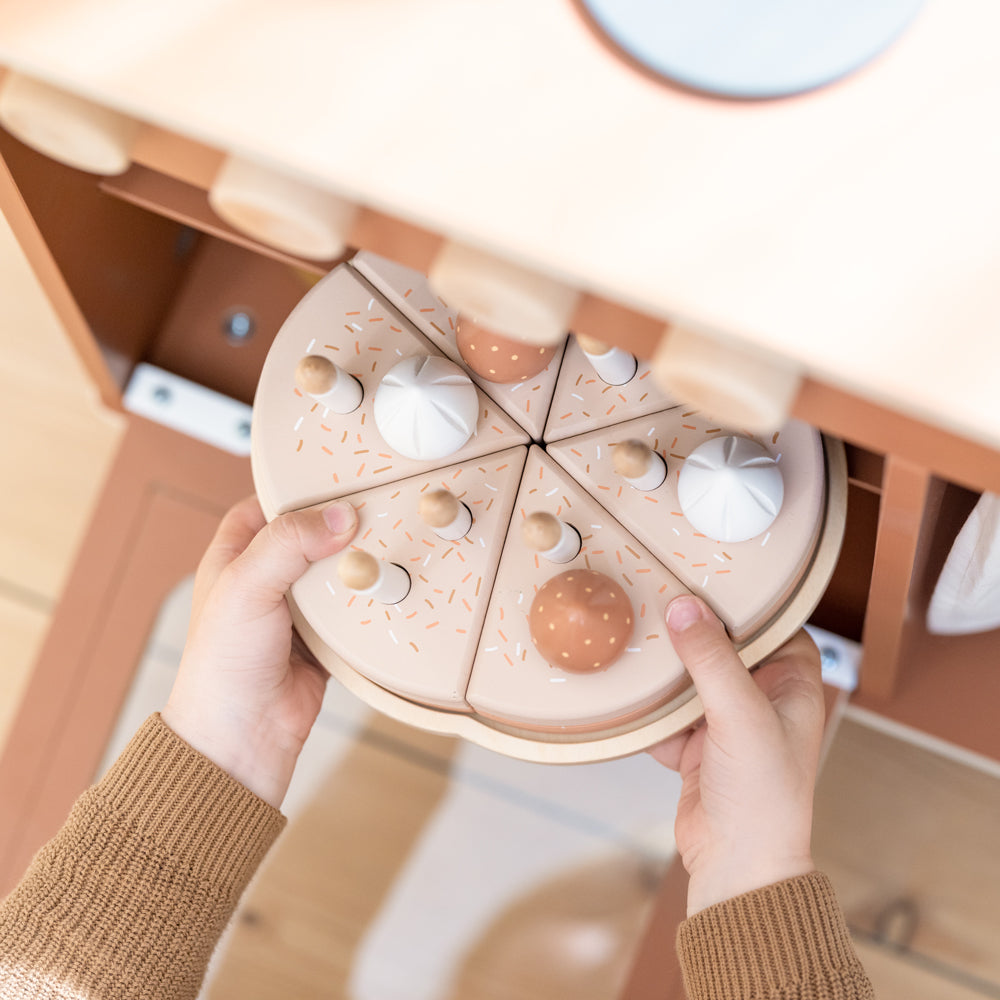 Geburtstagskuchen-Spielset aus Holz für Kinderküchen, 25 Teile, zeigt ein Kind, das Holz-Kuchenstücke spielerisch zusammenstellt.