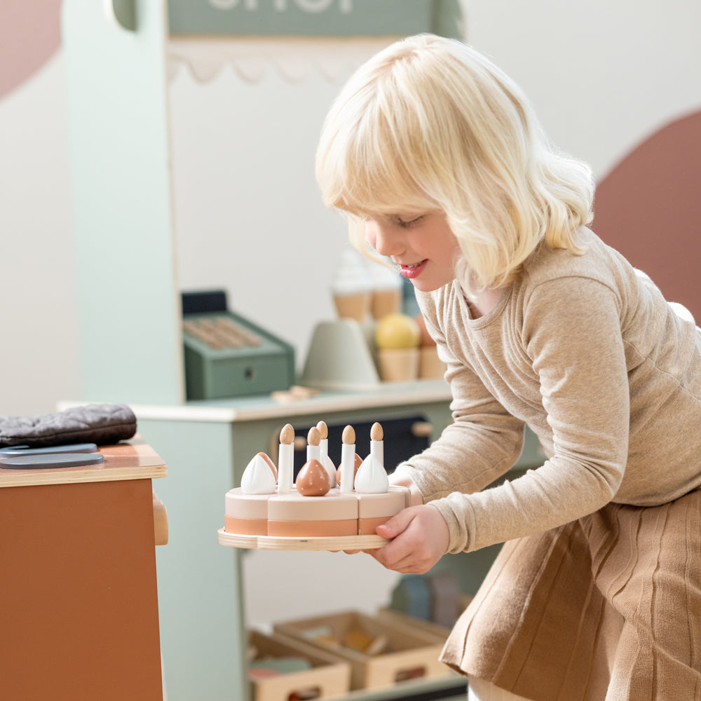 Kind spielt mit dem Geburtstagskuchen-Spielset aus Holz für Kinderküchen, 25 Teile, fördert Kreativität und soziale Fähigkeiten spielerisch.