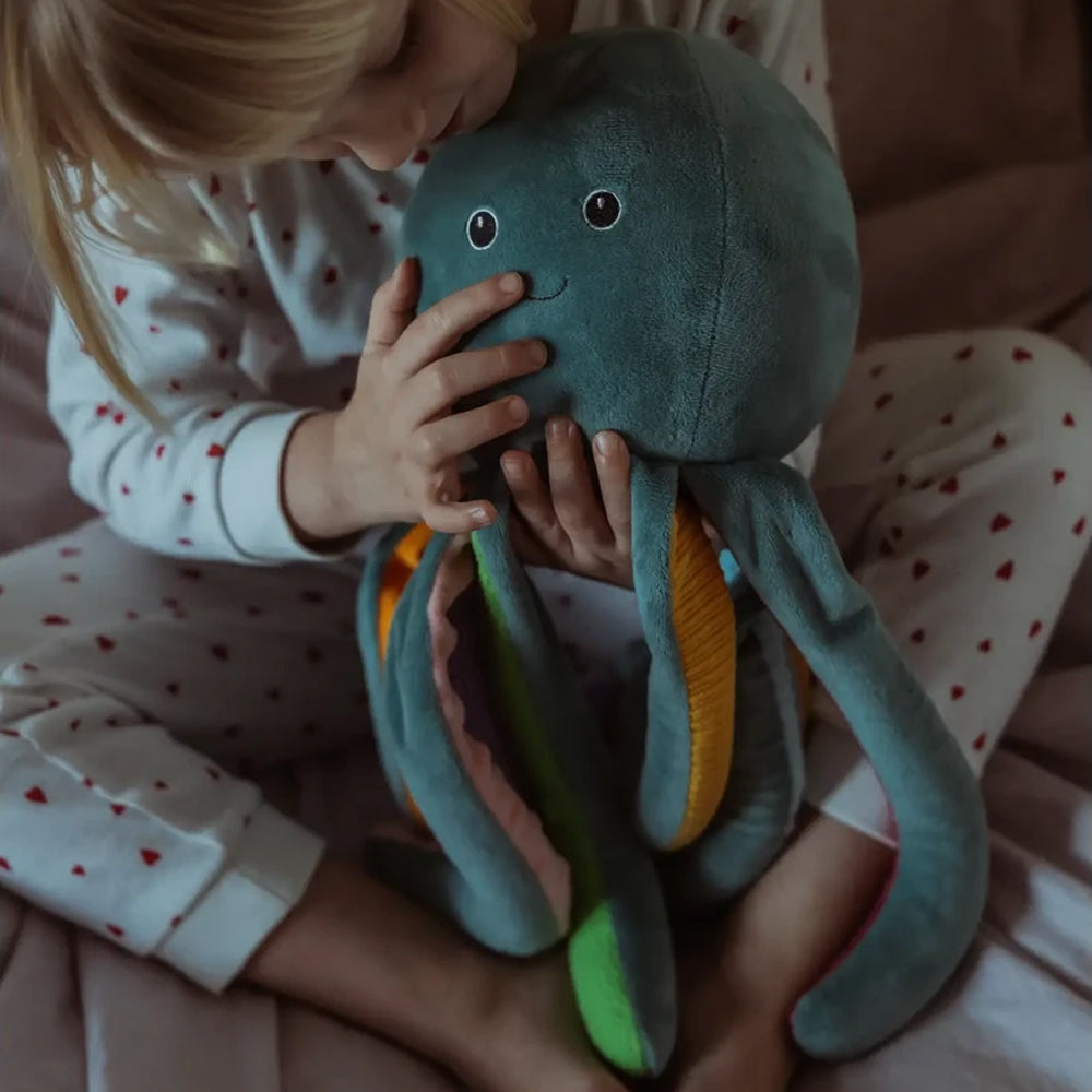 Kind hält liebevoll ein weiches Gewichts-Kuscheltier Plüsch-Oktopus aus der Meer Themenwelt Spielzeug & Spiele Kollektion.