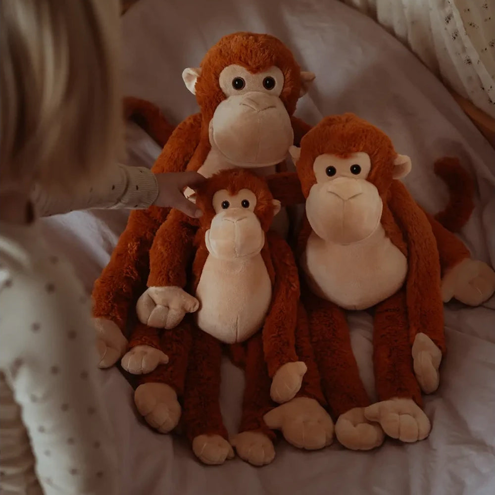 Drei kuschelige Plüsch-Affen in verschiedenen Größen auf einem Bett, ideal als Geschenk aus der Tierwelt Themenwelt Spielzeug & Spiele.