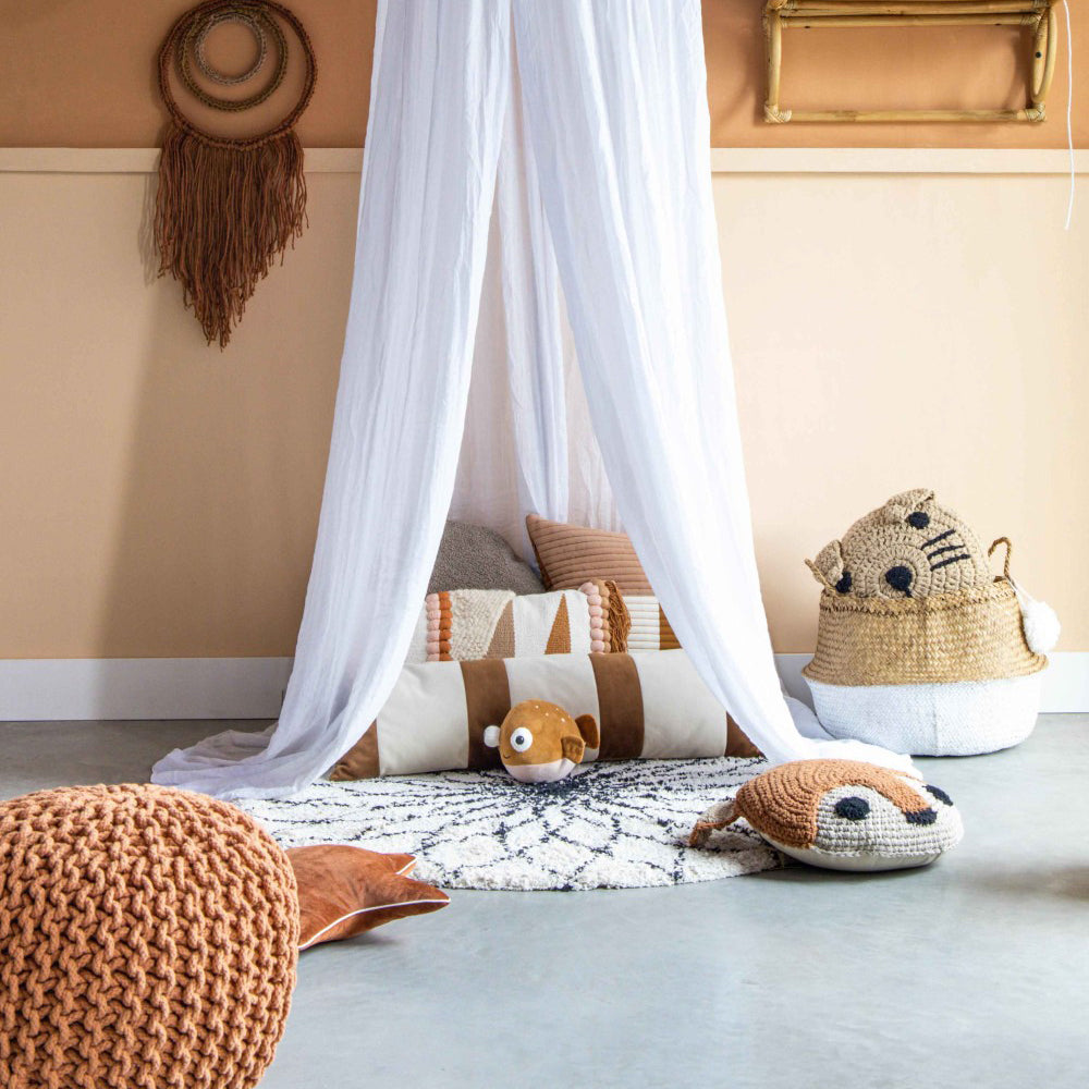 Gemütliche Kinderecke mit handgehäkeltem Tierwelt-Kissen, weichen Textilien und zartem Baldachin für ein behagliches Kinderzimmer-Ambiente.