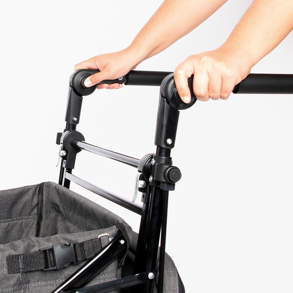 Hände halten den Griff des klappbaren Bollerwagens mit Bremse und Sonnendach aus der Kollektion Spielzeug & Spiele für Kinder.