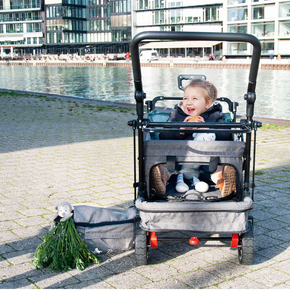 Kind sitzt lachend im klappbaren Bollerwagen Handwagen mit Sonnendach und Bremse, ideal für Spielzeug & Spiele sowie Bewegung im Freien.