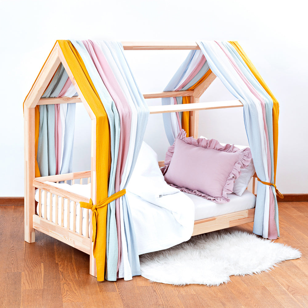 Kinderbett mit Holzrahmen und buntem Musselin-Himmel in Regenbogenfarben, gemütlich und spielerisch für das Kinderzimmer gestaltet.