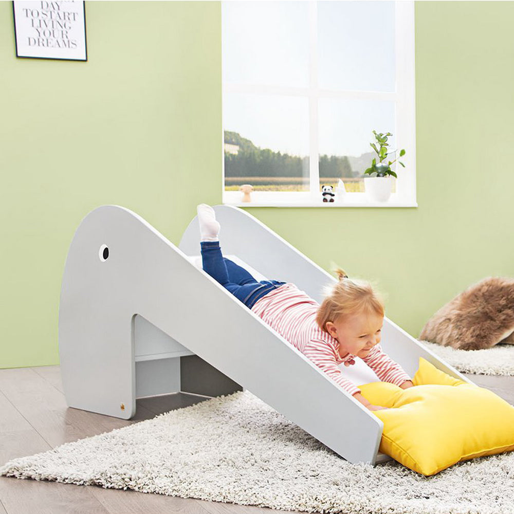 Kind spielt auf einer weißen Indoor Rutsche 118 cm Länge in einem hellen Raum mit Teppich und Kissen aus der Kollektion Spielmöbel.