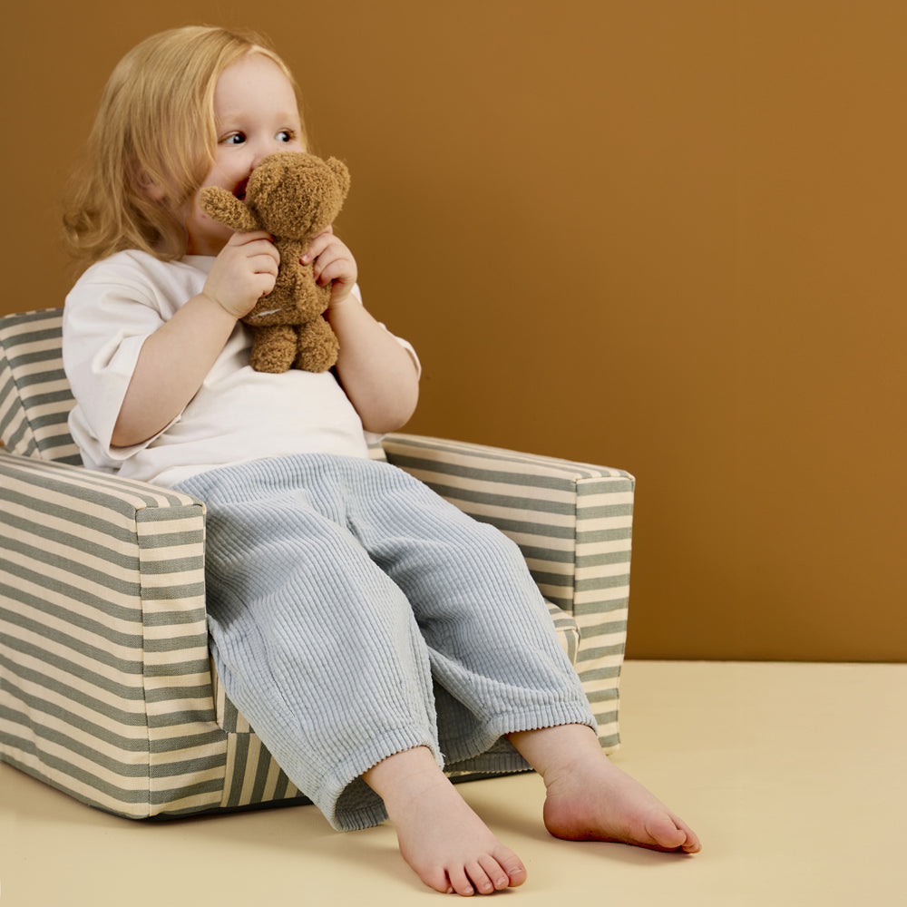 Kleines Kind sitzt entspannt im ausklappbaren Kinder Sessel aus Baumwolle, Produkt aus der Spielmöbel Kollektion für Kinder.