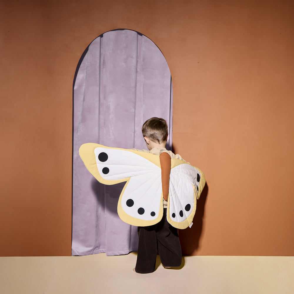 Kind trägt Kostüm Schmetterlingsflügel Maxi für Kinder 3-5 Jahre aus Spiel & Bewegung Kinder Kollektion vor lilafarbenem Vorhang