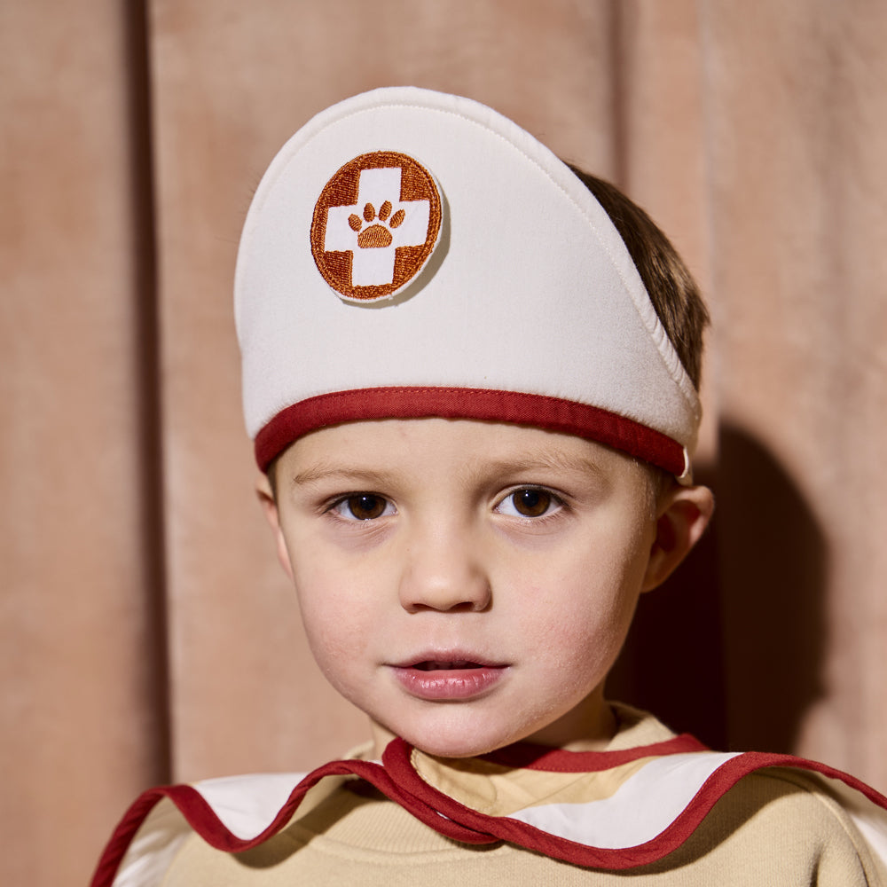 Kind trägt Kostümset Umhang Berufe in Weiß und Rot aus der Kollektion Spielzeug & Spiele für Kinder 3-5 Jahre, ideal für Rollenspiele.