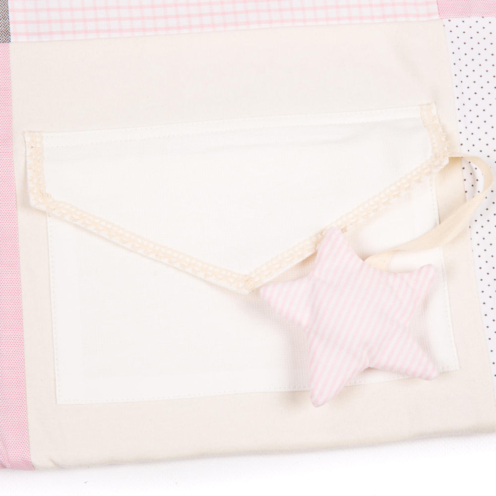 Nahaufnahme der rosa-weißen Patchwork Krabbeldecke mit Stern-Spielanhänger aus weicher Bio-Baumwolle für Babys.