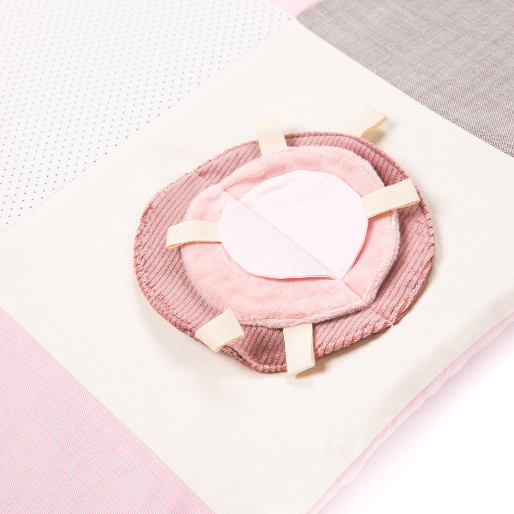 Weiche Spieldecke in Rosa mit taktilem Plüschelement zum Greifen und Fühlen, ideal für die motorische Förderung von Babys.