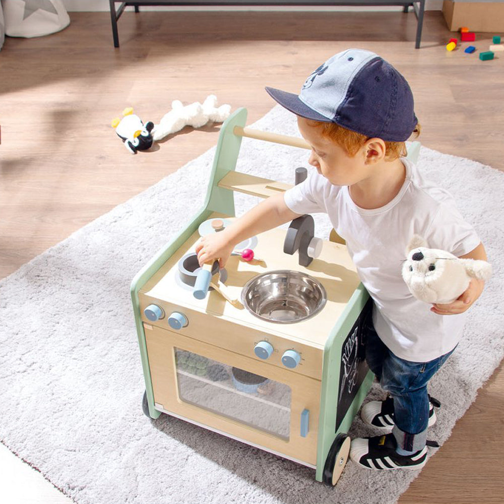 Kind spielt mit rollbarem Küchenwagen aus Holz, Teil der Kollektion Spielzeug & Spiele, Kinderküchen & Zubehör, fördert kreatives Spiel.