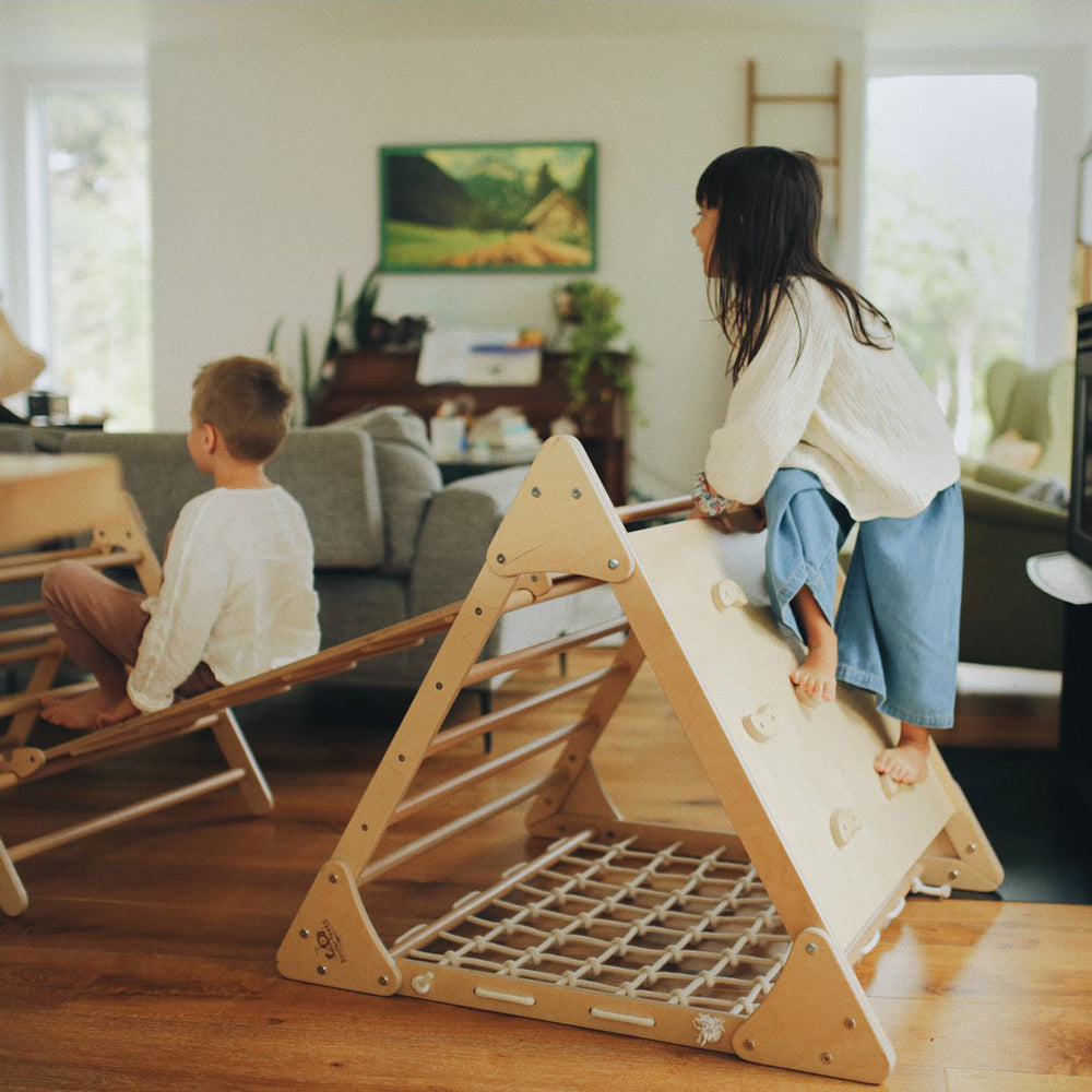 Kind spielt fröhlich am großen Pikler Kletterdreieck aus Buchen- und Birkenholz in gemütlichem Wohnumfeld Spiel & Bewegung Kinder
