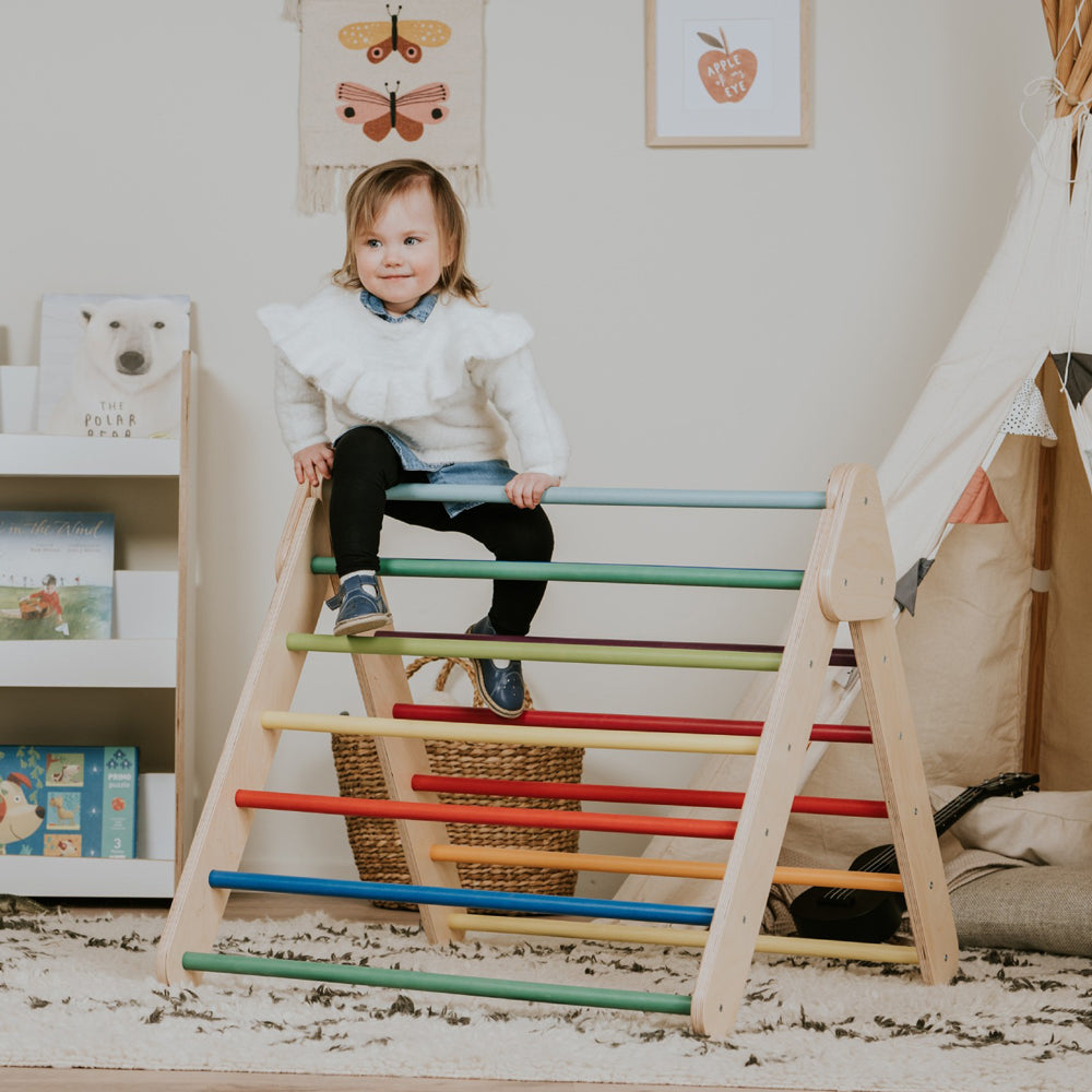 Kind spielt auf buntem Pikler Kletterdreieck aus Holz im gelben Kinderzimmer aus der Pünktchen & Herzchen Themenwelt.
