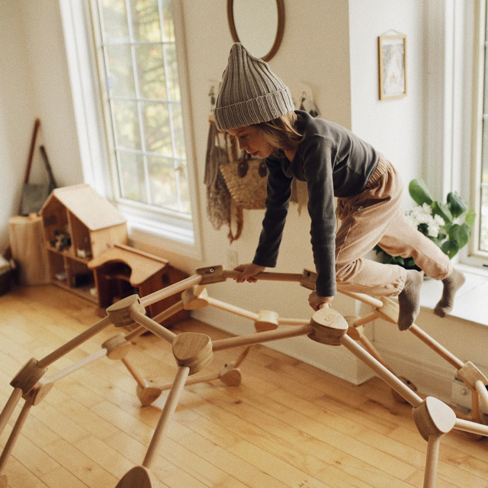 Kind klettert spielerisch an der nachhaltigen Pikler Kletterkuppel aus Buchenholz und Bambus für Spiel & Bewegung Kinder.