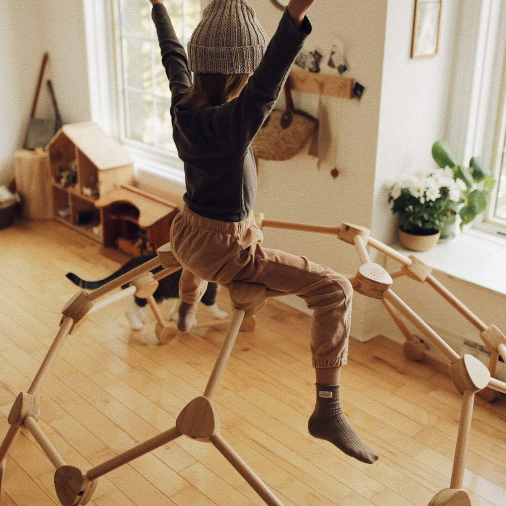 Kind spielt auf der Pikler Kletterkuppel aus Buchenholz und Bambus – fördert Bewegung, Gleichgewicht und Kreativität im Kinderzimmer.