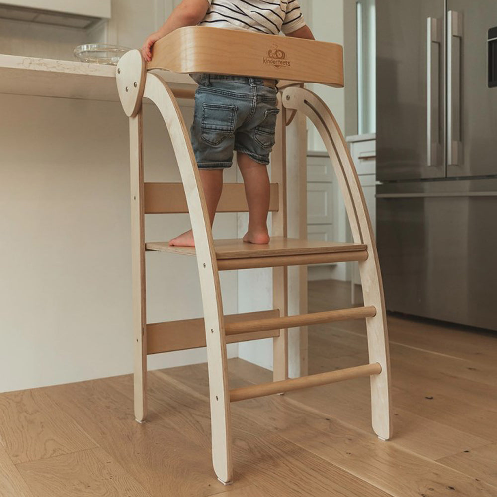Kinder stehen sicher auf klappbarem Pikler Lernturm aus Birkenholz in moderner Küche, fördert Selbstständigkeit und spielerisches Lernen.