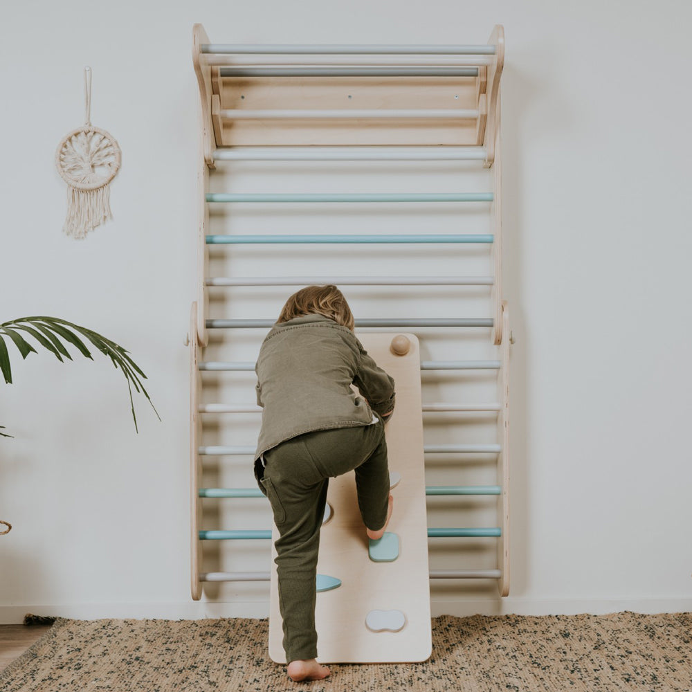Kind erklimmt Pastellfarbene Erweiterung 2in1 Rampe für Kletterdreieck aus Holz im modernen Kinderzimmer mit Teppich und Pflanzenwanddeko.