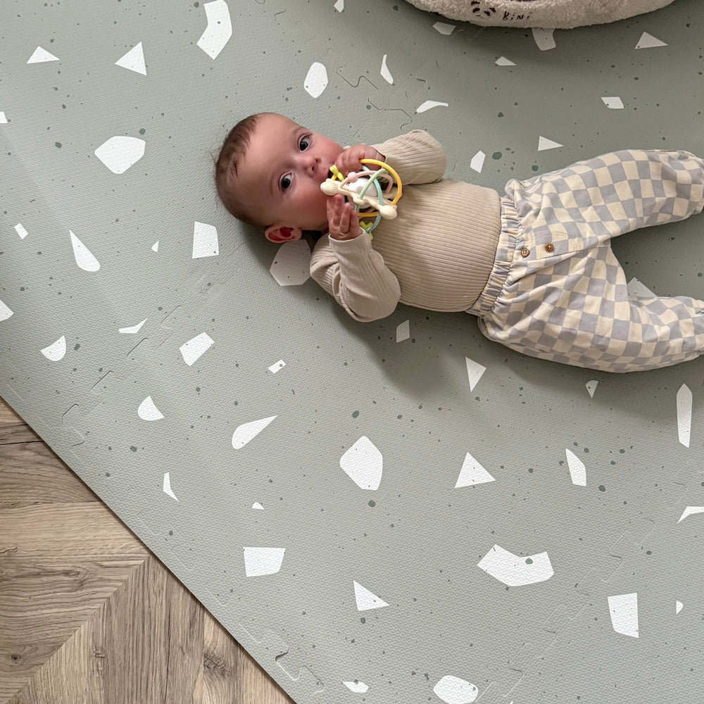 Baby liegt entspannt auf Spiel- & Puzzlematte 120 x 180 cm in Salbei Terrazzo, ideal für Spielzeug & Bewegung Kinder zu Hause