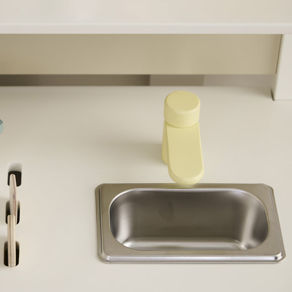 Detailaufnahme einer weißen Holz-Spielküche mit gelbem Wasserhahn und spülmaschinenähnlichem Becken aus Spielzeug & Spiele Kinderküchen Zubehör