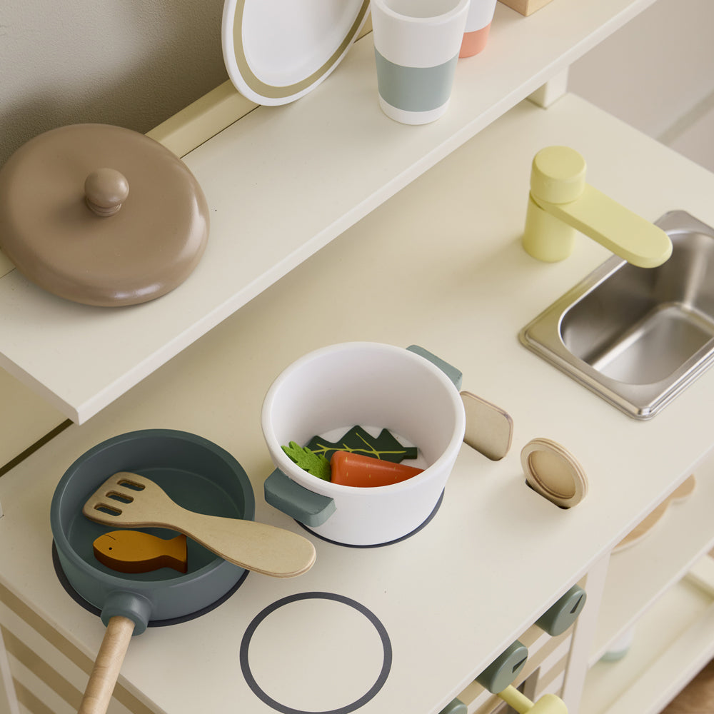 Weißes Spielküche aus Holz mit Zubehör wie Pfanne, Topf, Kochlöffel und farbigen Tassen aus der Kollektion Kinderküchen & Zubehör.