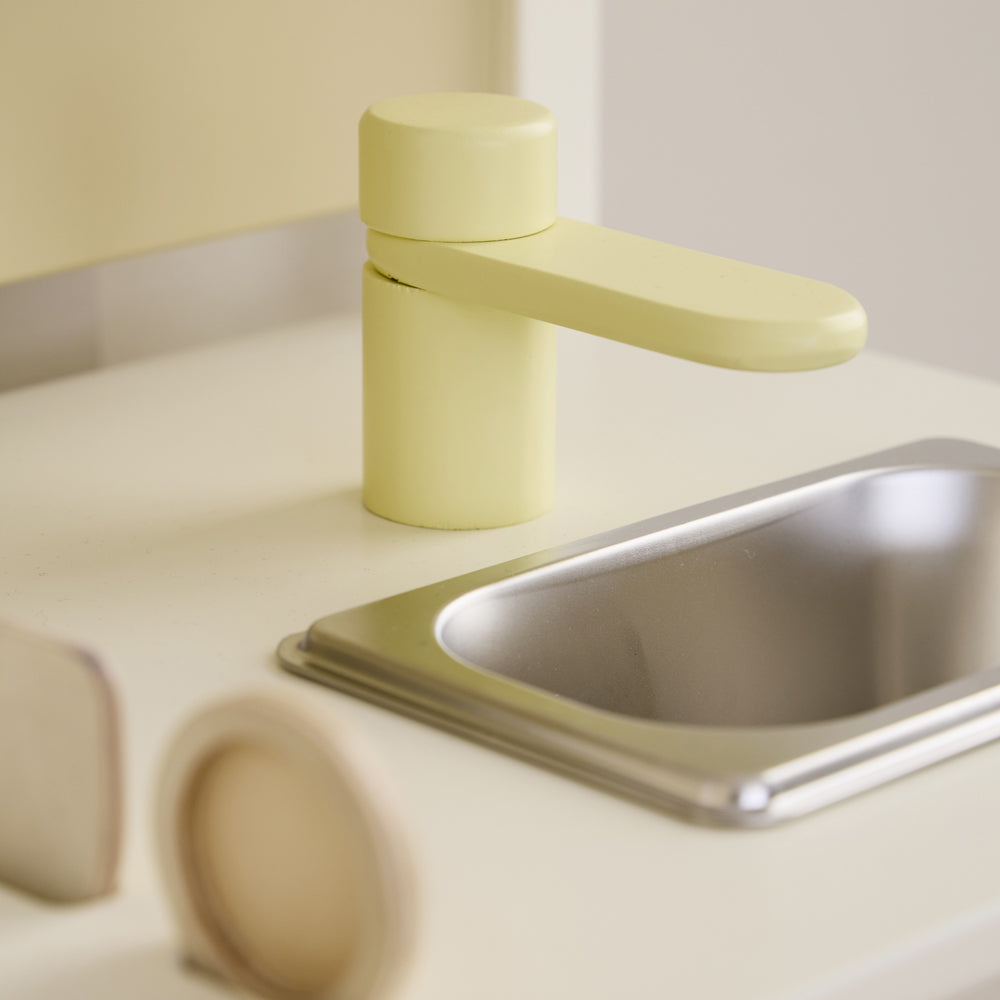 Nahaufnahme eines gelben Wasserhahns neben einer Metallspüle aus der Spielzeug & Spiele Kollektion Kinderküchen & Zubehör Sale Neu