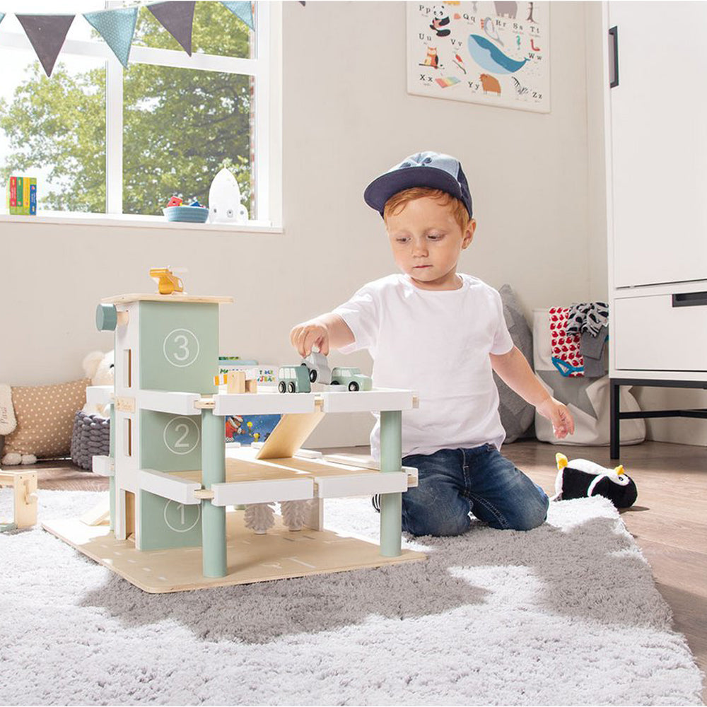 Kind spielt mit Spielparkhaus aus Holz mit Fahrzeugen und Zubehör aus der Motorik- & Holzspielzeug Themenwelt für Kinderzimmerspaß