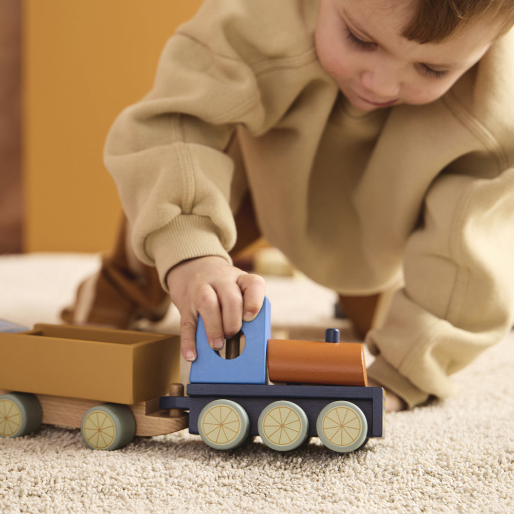 Kleines Kind spielt mit einem bunten Holzspielzeugzug aus der Themenwelt Bauernhof & Garten, ideal für Motorik & Spielspaß.