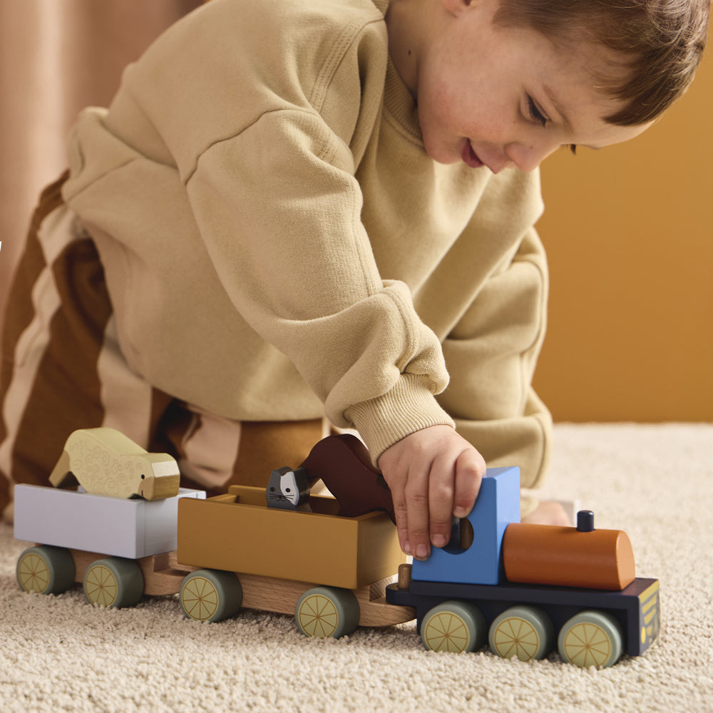 Kind spielt begeistert mit Holzspielzeugzug mit 5 Bauernhoftieren aus der Motorik- & Holzspielzeug Kollektion für Kinder.
