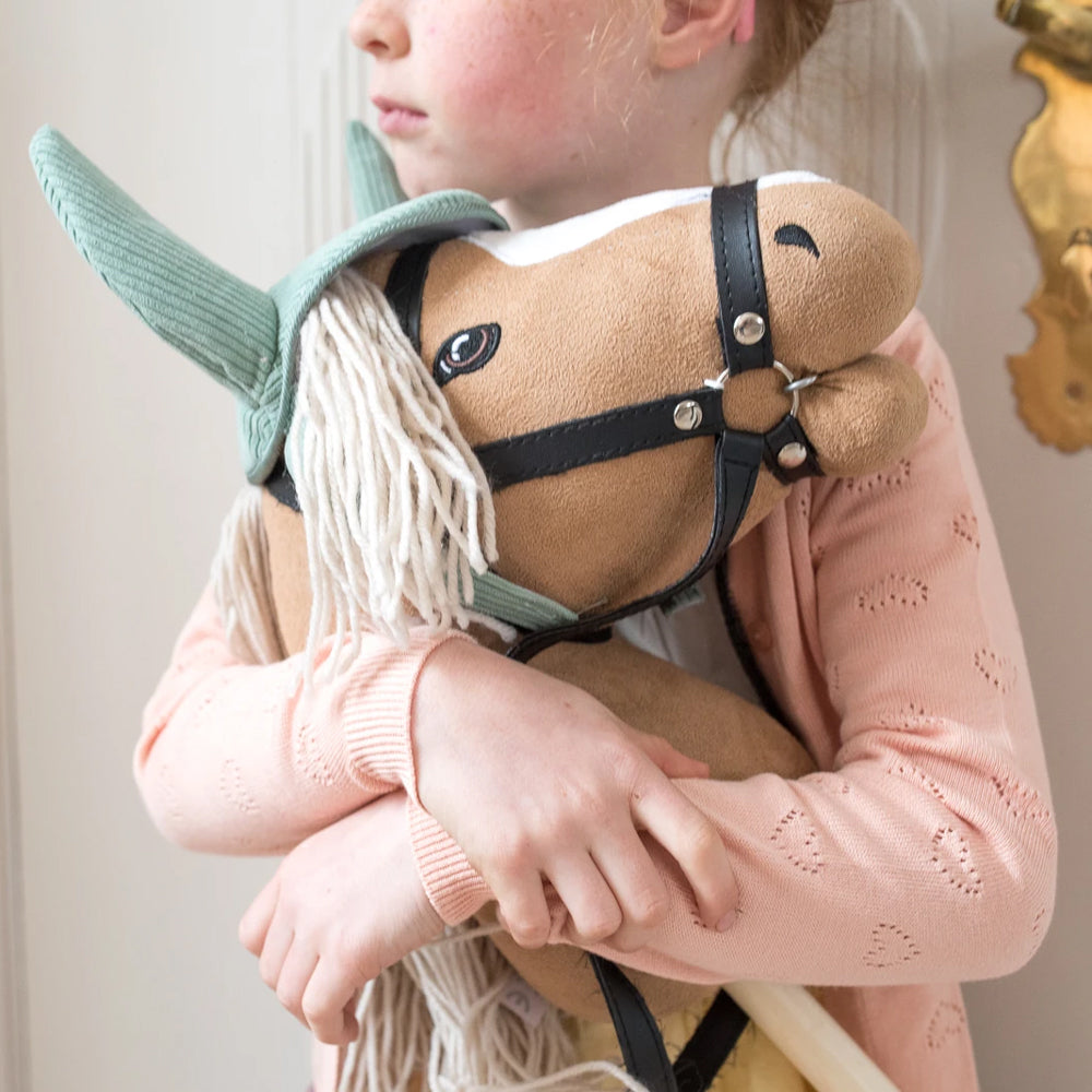 Kind umarmt beige Steckenpferd mit offenem Mund aus Spielzeug & Spiele, Hobby Horsing, Tierwelt Themenwelt Kollektion