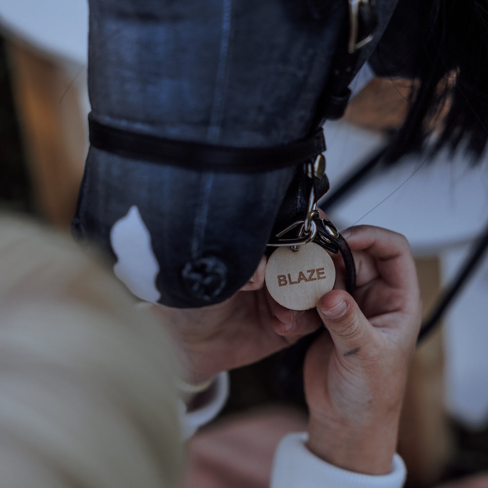 Kinderhand hält graues Steckenpferd mit offenem Mund und personalisiertem Anhänger „BLAZE“ aus der Hobby Horsing Tierwelt Themenwelt.