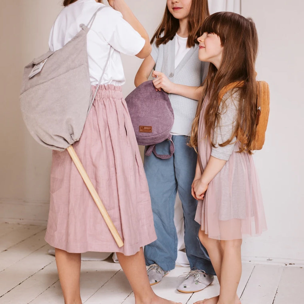 Drei Kinder mit Rucksäcken spielen zusammen in heller Kleidung, passend zu Spielzeug & Spiele, Spiel & Bewegung Kinder Themenwelt.