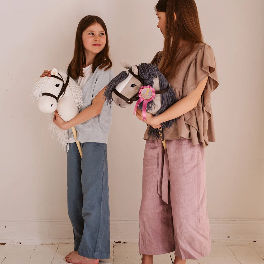 Zwei Mädchen spielen mit Steckenpferden in grau aus der Themenwelt Spielzeug & Spiele, Hobby Horsing und Tierwelt.