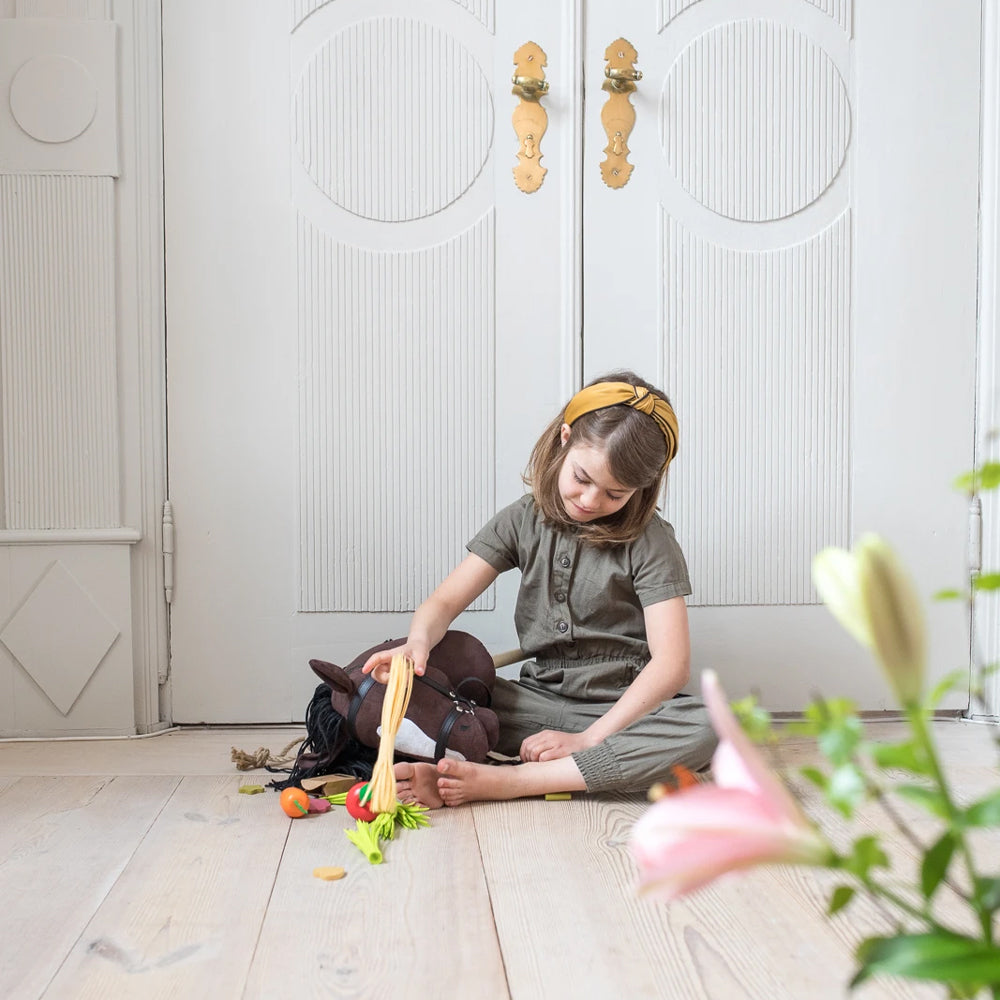 Mädchen spielt drinnen mit braunem Steckenpferd offenes Maul aus der Themenwelt Spiel & Bewegung Kinder und Hobby Horsing.