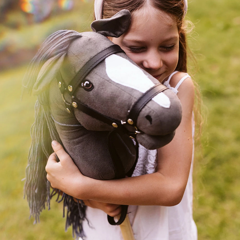 Mädchen umarmt Steckenpferd offenes Maul in grau aus der Themenwelt Spielzeug & Spiele und Hobby Horsing Kinderfreude.