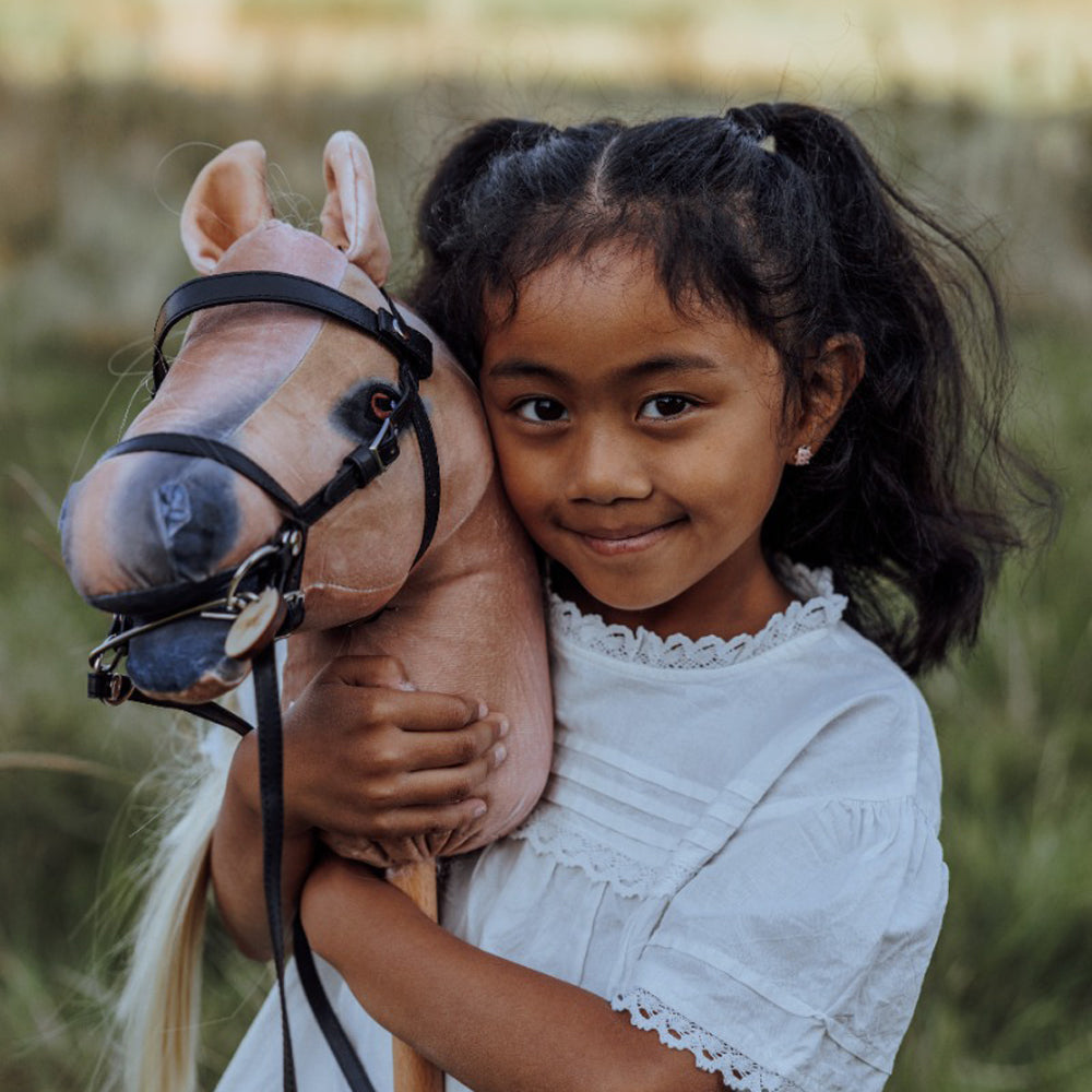 Mädchen umarmt blondes Steckenpferd aus der Themenwelt Tierwelt und Spiel & Bewegung Kinder, ideal für Spielzeug & Geschenke Sammlung.