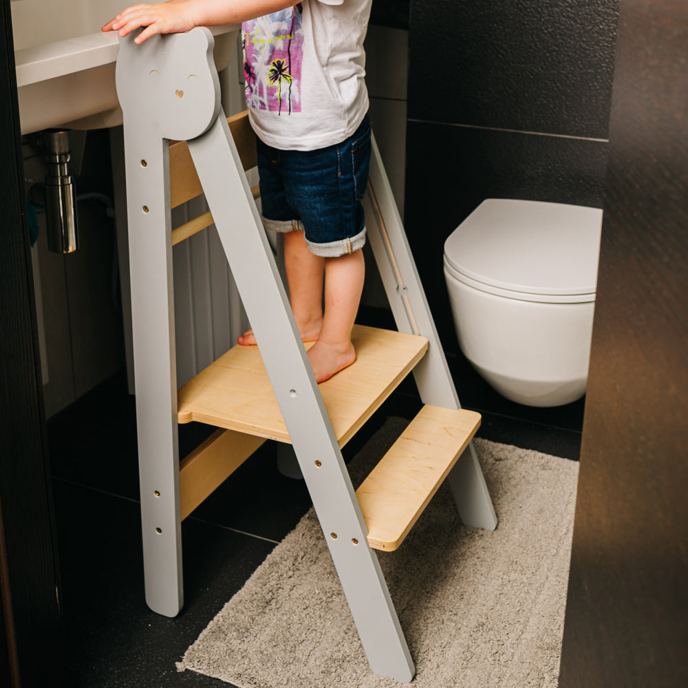 Kind auf Tritthocker Lernstuhl klappbar mit 2 Stufen, höhenverstellbar, im modernen Badezimmer für mehr Selbstständigkeit.